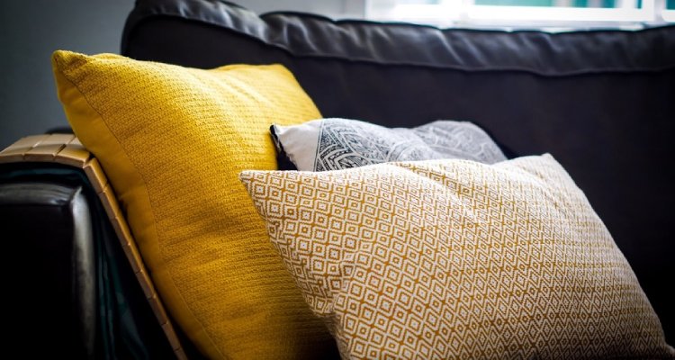 Żółte i szare poduszki na czarnej kanapie